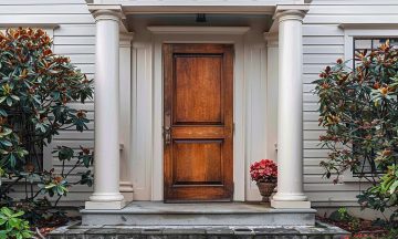 ai-generated-the-main-entrance-door-of-the-house-features-a-charming-wooden-front-door-with-a-gabled-porch-and-landing-photo (1)
